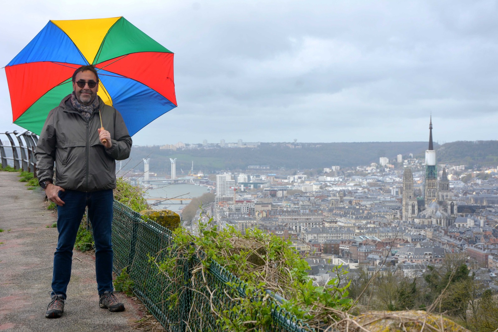 Portrait de Franck Adam devant Rouen, sous un parapluie coloré